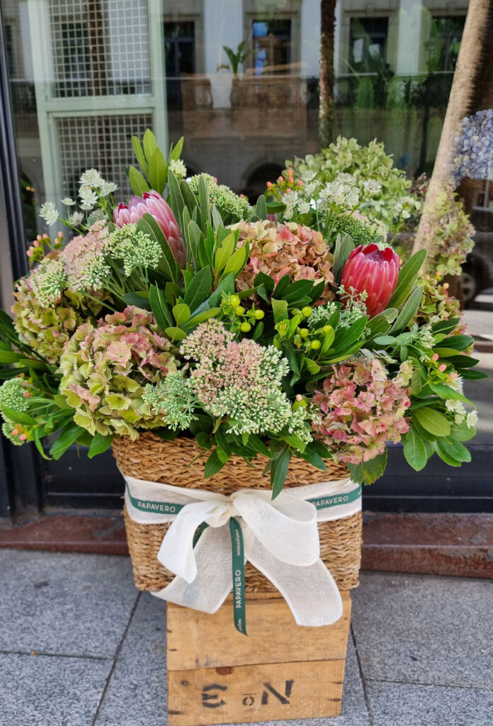 arreglo de flores en cesta de mimbre colocado en el escaparate de la floristería papavero