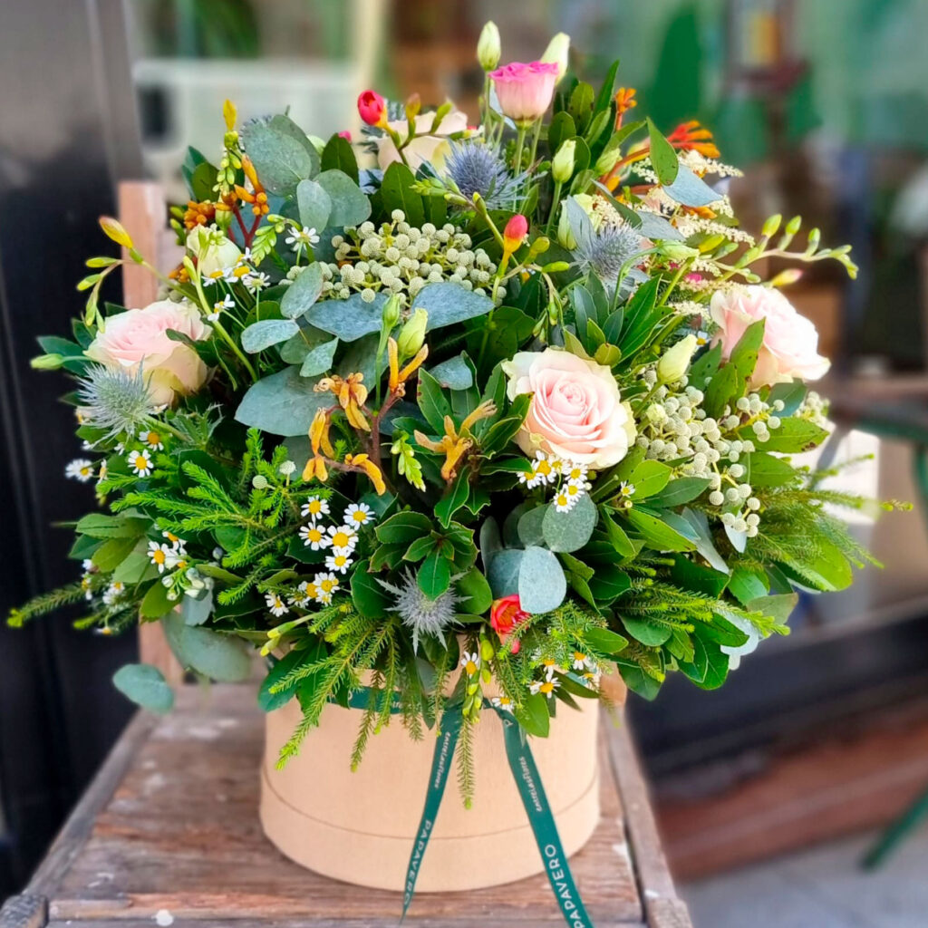 flores frescas de temporada en una sombrerera mediana al estilo papavero