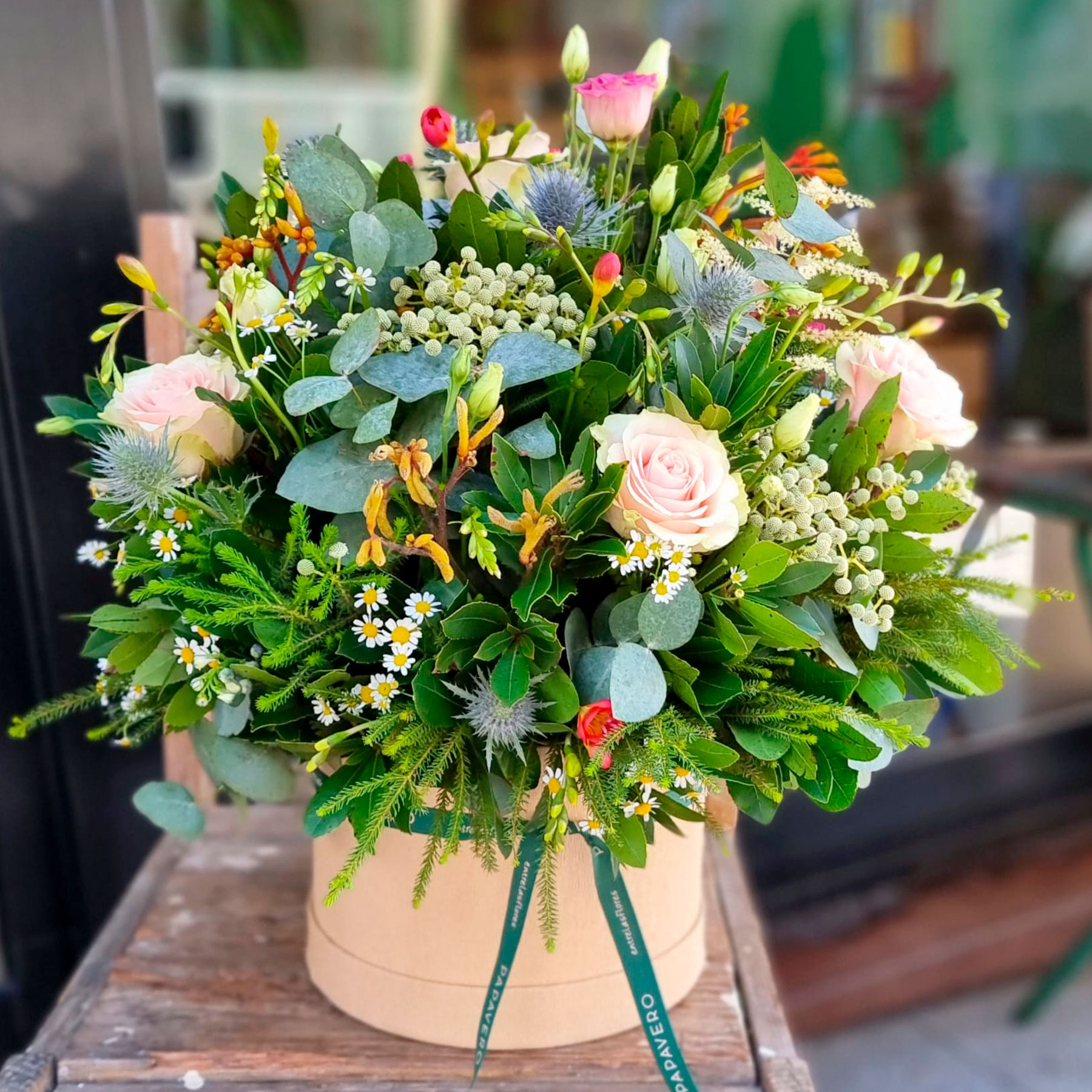 flores frescas de temporada en una sombrerera mediana al estilo papavero