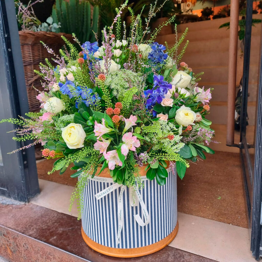 arreglo floral en tonos rosas violetas y verdes realizado en una sombrerera de madera de tamaño XL